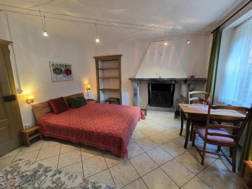a bedroom with a bed and a table and a fireplace at Garni Cà Stella in Bignasco