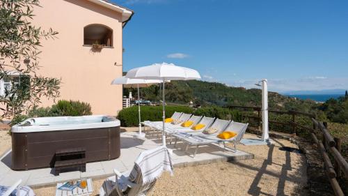 a hot tub on a patio with chairs and an umbrella at VILLA PERELLE 8, Emma Villas in Rio nellʼElba