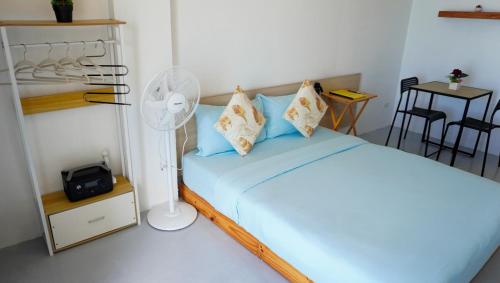 a bedroom with a bed with blue sheets and a fan at Happy Island Inn in Virac