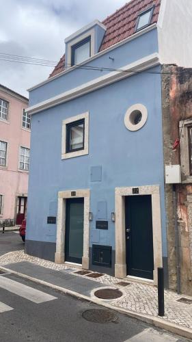a blue building with two doors on a street at Casa de Saudade - Refúgio junto ao mar in Paço de Arcos
