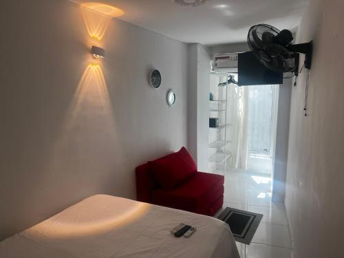 a bedroom with a bed and a red chair at Estudio 1 Cerca PLAYA Y CENTRO HISTORICO in Santa Marta