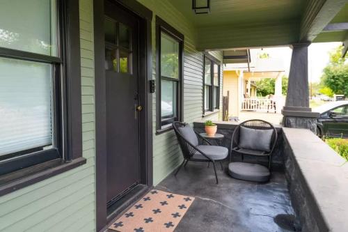 a porch with two chairs and a table next to a door at The Modern Cottage in Bend