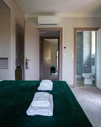 a bedroom with a green bed with towels on it at Le Cro-Magnon - hôtel - piscine - climatisation in Les Eyzies-de-Tayac
