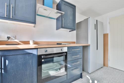 a kitchen with blue cabinets and a sink at Cosy 3-Bedroom House Near Caerphilly Castle in Caerphilly
