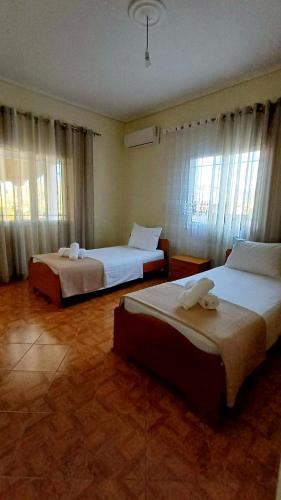 two beds in a hotel room with windows at Villa Albano in Delvinë
