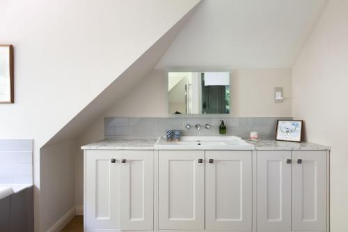 a white bathroom with a sink and a mirror at Nest Lodge by The Butler Collection in Pulborough
