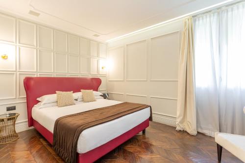 a bedroom with a large bed with a red headboard at Hotel The Corner Roma in Rome