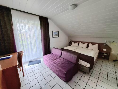 a bedroom with a large bed and a purple couch at Hotel Pappelhof in Weidenbach