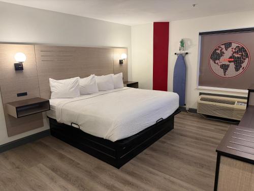 a hotel room with a large bed with white sheets at Ramada by Wyndham Albany GA in Albany