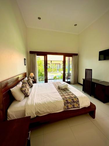 a bedroom with a large bed and a desk at Plawa Bali Guest House in Canggu