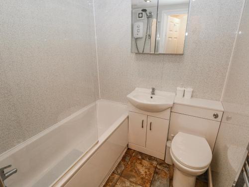 a white bathroom with a toilet and a sink at Trelessy Lodge in Amroth