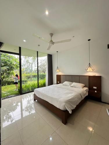 a bedroom with a large bed and large windows at Khu Nghỉ Dưỡng Ivory Villa Resort in Lương Sơn
