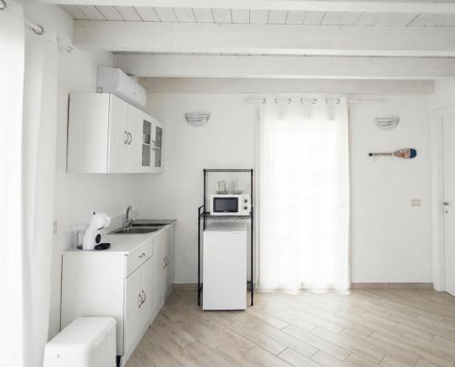 a white kitchen with a refrigerator and a microwave at Sole & Luna in Elmas