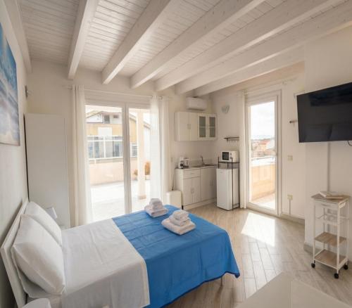 a white bedroom with a blue bed and a kitchen at Sole & Luna in Elmas