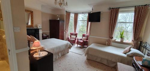 a hotel room with two beds and a table and chairs at The Limes in Stow on the Wold