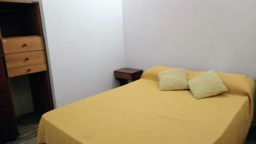 a bedroom with a yellow bed with two pillows at Complejo El Tala in Mina Clavero