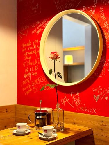 a table with a vase with a flower and a mirror at Heaven AT 11, your Deluxe Studio with personal bathroom, kitchenette & terrace in Ghent
