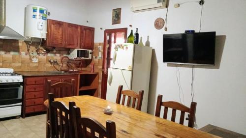 a kitchen with a wooden table and a refrigerator at Complejo El Tala in Mina Clavero