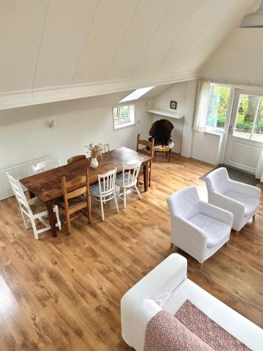 a living room with a wooden table and white chairs at Boerderijhuisje 22 - Landelijk logeren bij Sneek in Loënga