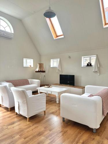 a living room with white couches and a tv at Boerderijhuisje 22 - Landelijk logeren bij Sneek in Loënga
