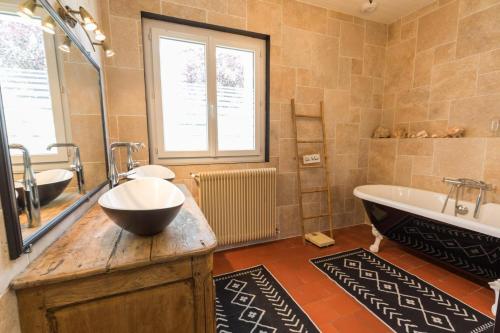 un bagno con due lavandini e una vasca e una grande finestra di Maison de mordoit a Pissos