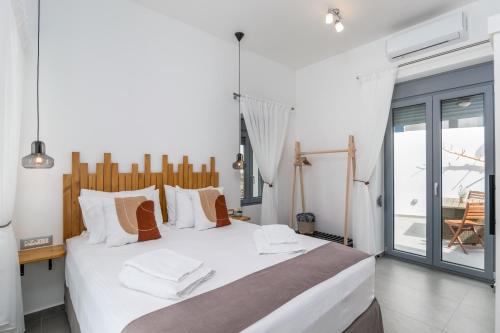 a bedroom with a large white bed and a balcony at Almyra House in Adamantas