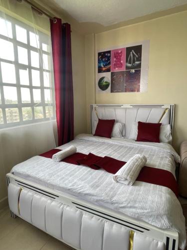 a bedroom with a large white bed with red pillows at The Homely Retreat in Thika