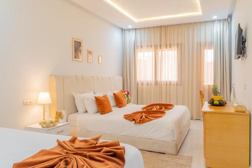 a bedroom with two beds with orange pillows at Hotel Golden Sunset Dakhla in Dakhla