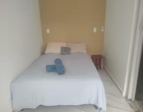 a white bed with a pair of blue shoes on it at Kitnet Terreo Privada 1 in Conde