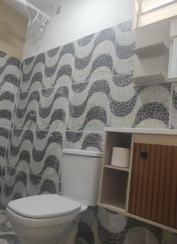 a bathroom with a toilet and a patterned wall at Kitnet Terreo Privada 1 in Conde