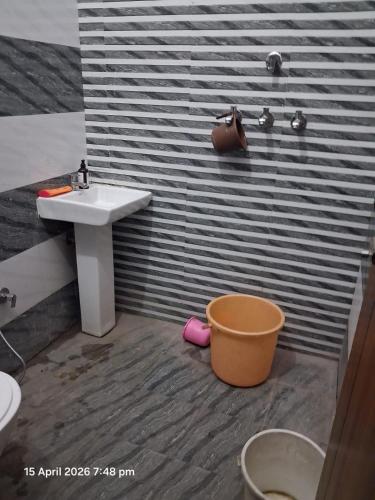 a bathroom with a sink and a toilet and a bucket at SG Homestay in Amritsar