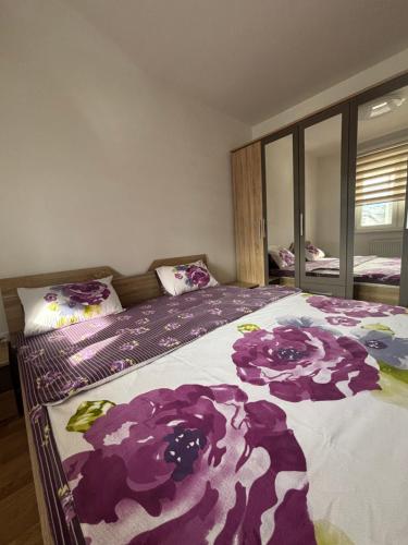 a bedroom with a bed with purple flowers on it at Apartman MARIJA in Pale