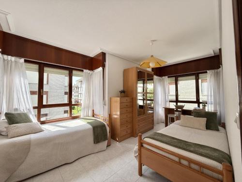 a bedroom with two beds and a desk and windows at Apartamento Salceda - 6901 in Noja