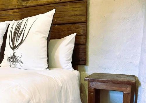 a white bed with a wooden headboard and a table at The Storybook Nook in Kaapsehoop