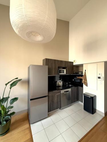 a kitchen with a stainless steel refrigerator and a large light fixture at Appartement calme et lumineux au cœur d'Arles in Arles