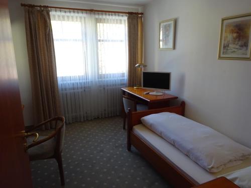 a bedroom with a bed and a desk with a computer at Schloß-Hotel Hirschau in Hirschau