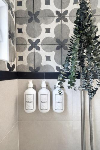 three white bottles on a shelf in a bathroom at Rivers End Guesthouse in Hope Bay