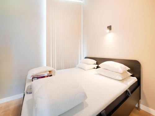 a small room with a bed with white sheets and pillows at Bollen in Oud-Ade