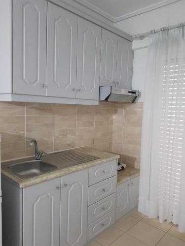 a kitchen with white cabinets and a sink at Victoria Studio Himara in Himare