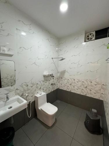 a bathroom with a white toilet and a sink at Halfmoon Homestay in Kalyānpur