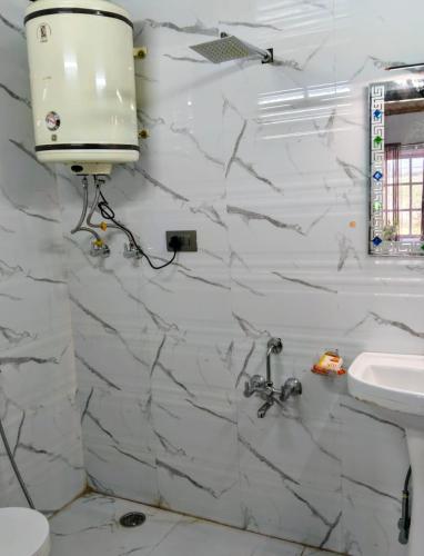 a bathroom with a sink and a white marble wall at The Holt Gardens in Srinagar