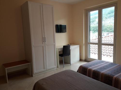 1 dormitorio con 2 camas, escritorio y ventana en Il Bel Risveglio, en Atena Lucana