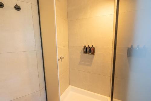 a shower with a glass door with bottles in it at Moreno Camp - Glamping with a view in El Calafate