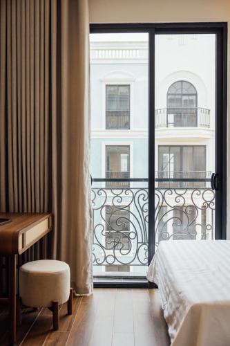 a bedroom with a balcony with a bed and a desk at Lavena Boutique Hotel in Sầm Sơn