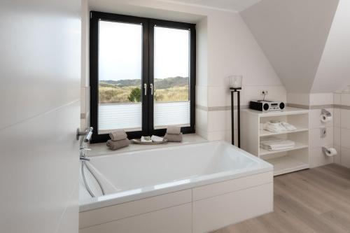 a white bathroom with a tub and a window at Reethuus Nord in Juist
