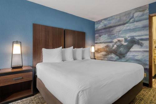 a bedroom with a large bed and a painting of a horse at Best Western Winners Circle in Hot Springs