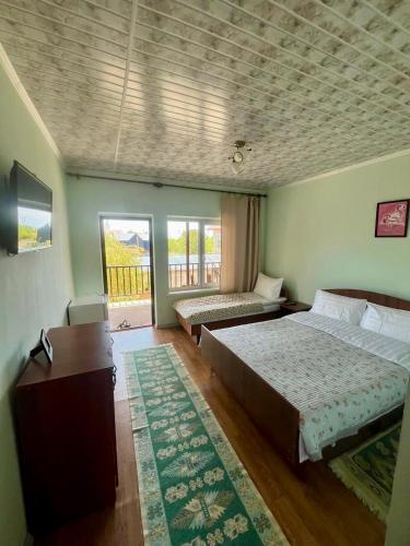 a bedroom with two beds and a desk and a window at AltynAi Guest House in Cholpon-Ata