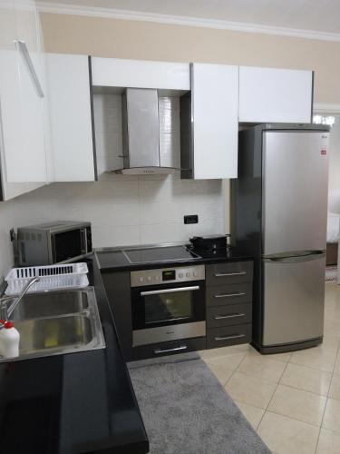 a kitchen with stainless steel appliances and white cabinets at Nik's Cozy Apartment in Berat