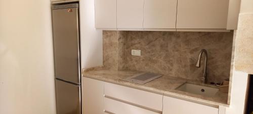 a kitchen with a sink and a refrigerator at Planta baja junto al mar con barbacoa in El Brosquil