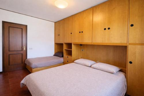 a bedroom with two beds and wooden cabinets at SunLake Apartment in Colico